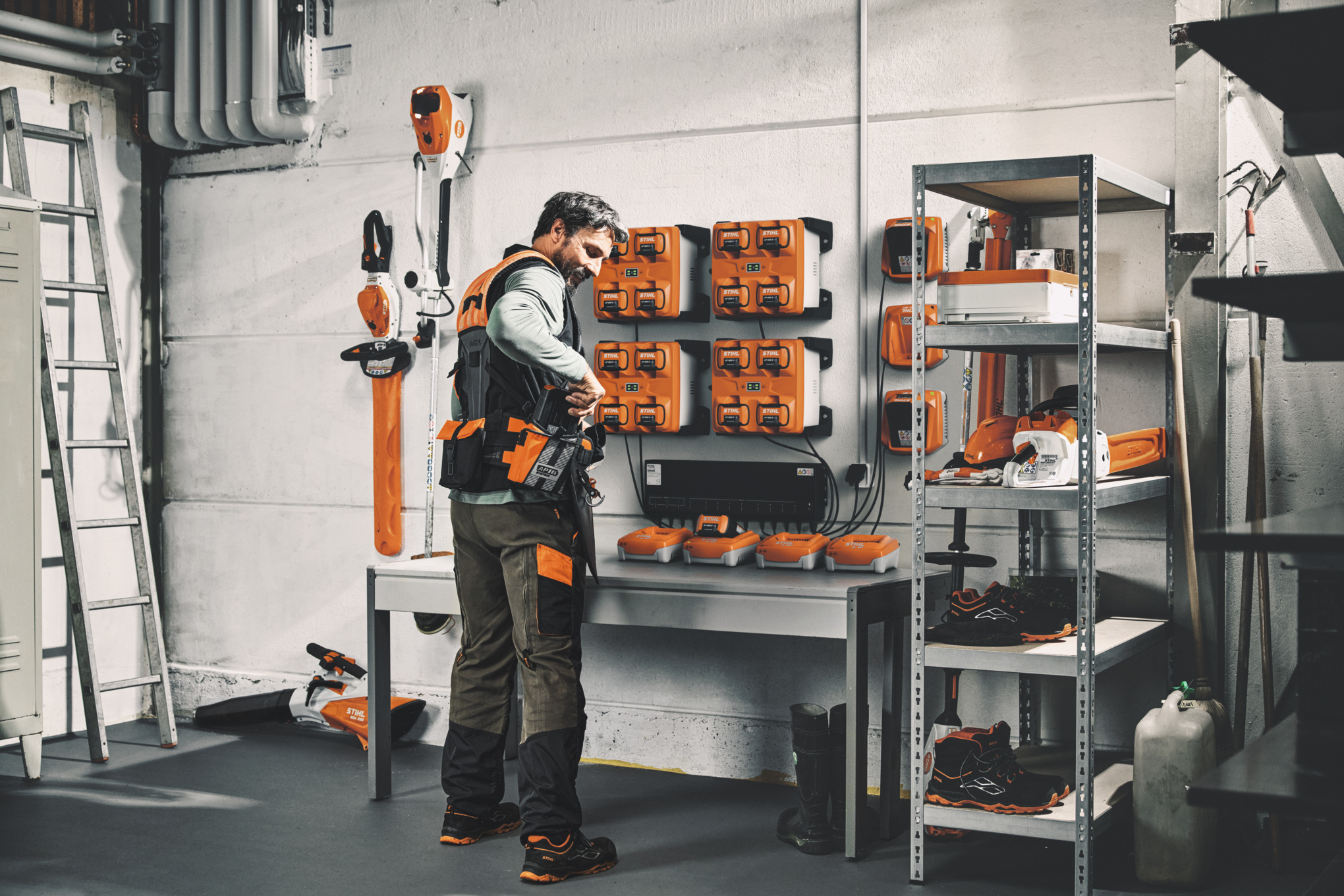Mężczyzna w warsztacie przygotowuje swój modułowy system nośny ADVANCE X-Flex z załadowanymi akumulatorami z systemu zarządzania ładowaniem CM 12.