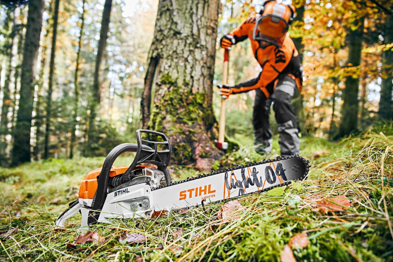 Mężczyzna w ubraniu ochronnym w lesie, na pierwszym planie pilarka spalinowa STIHL MS 261 C-M z prowadnicą Light 04