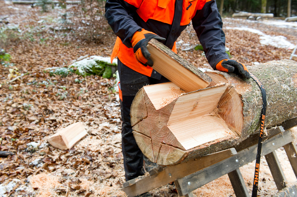 Make a wooden star: a person removing excess pieces from a log partly carved into a star shape