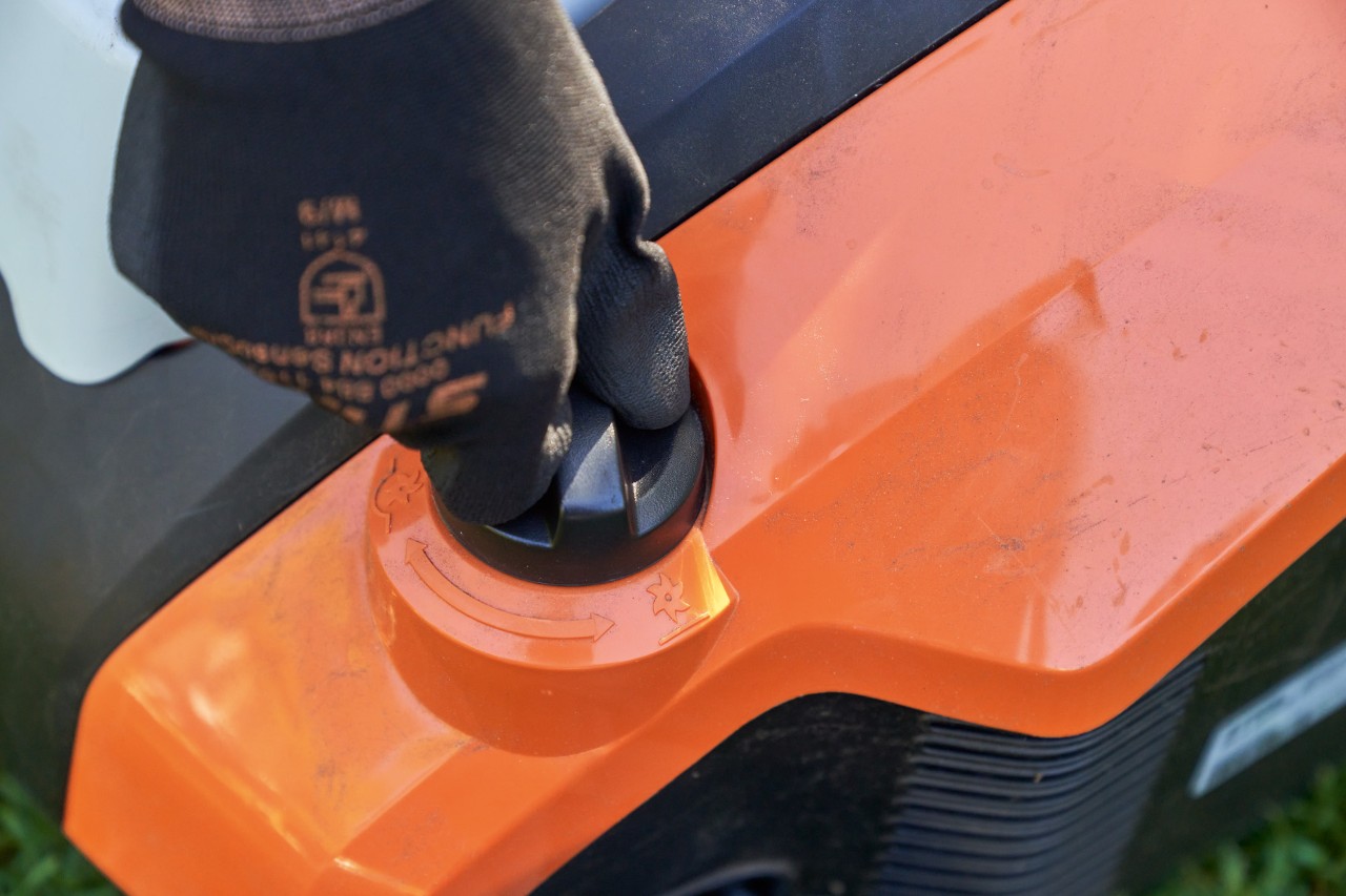 Zbliżenie: Ręka w rękawicach roboczych STIHL FUNCTION SENSOTOUCH obraca uchwyt obrotowy akumulatorowego aeratora do trawnika STIHL RLA 240.