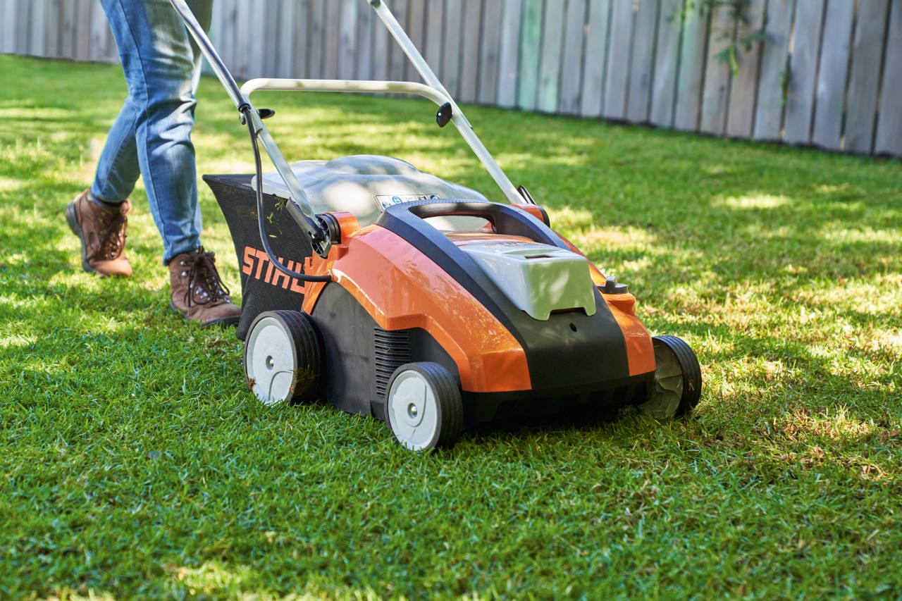 Akumulatorowy aerator do trawnika STIHL RLA 240 podczas napowietrzania zielonego trawnika