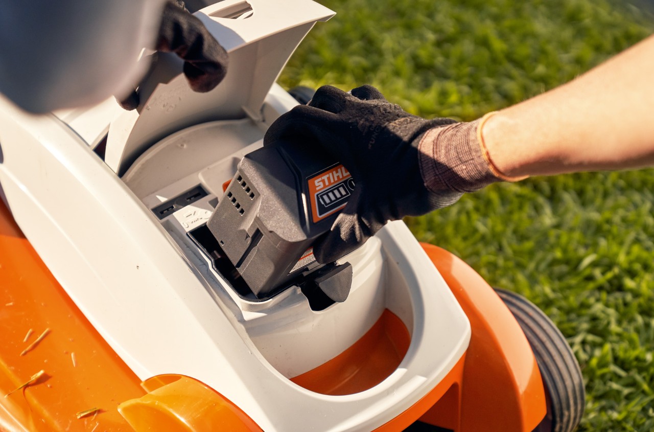 Osoba wyjmuje akumulator z kosiarki akumulatorowej STIHL RMA 339C w celu przechowywania w zimie