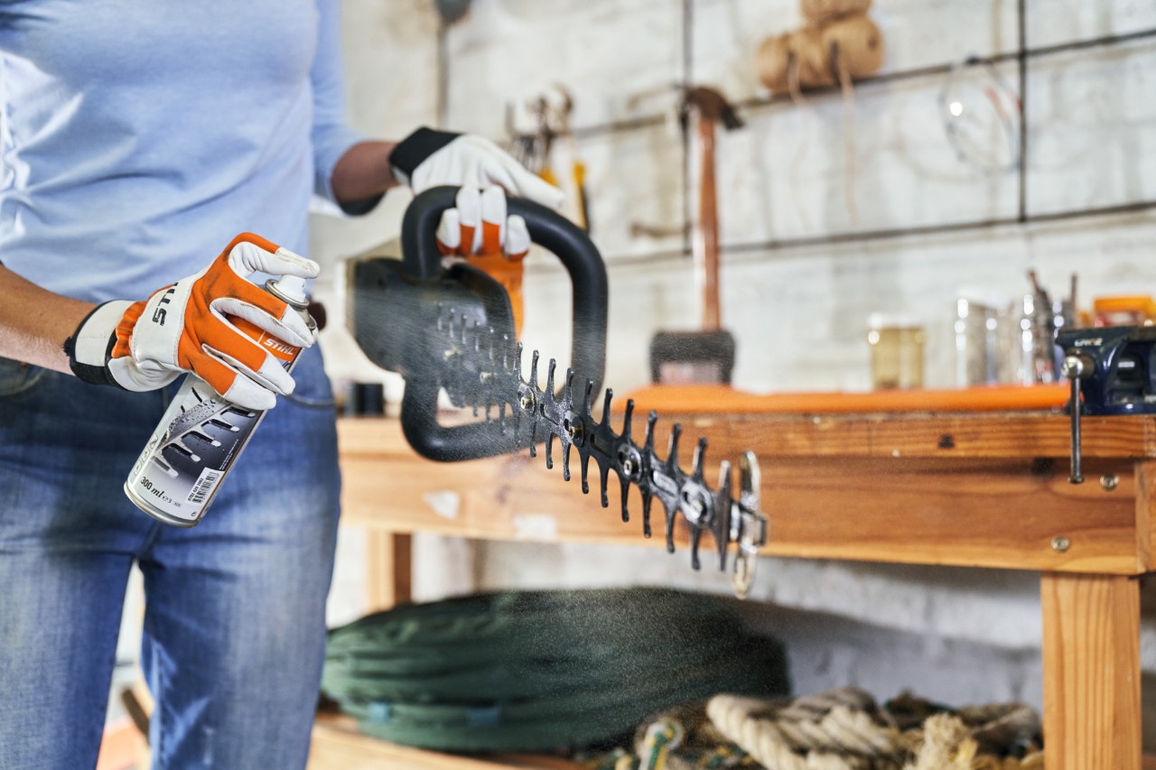  STIHL Benzin-Heckenschere HS 82 T wird auf grünem Rasen eingesprüht, um sie zu reinigen