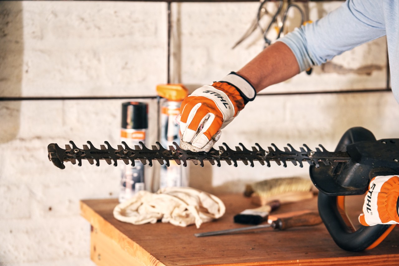 STIHL Benzin-Heckenschere HS 82 T liegt vor der Wartung zwischen grünen Blättern auf einer Treppe