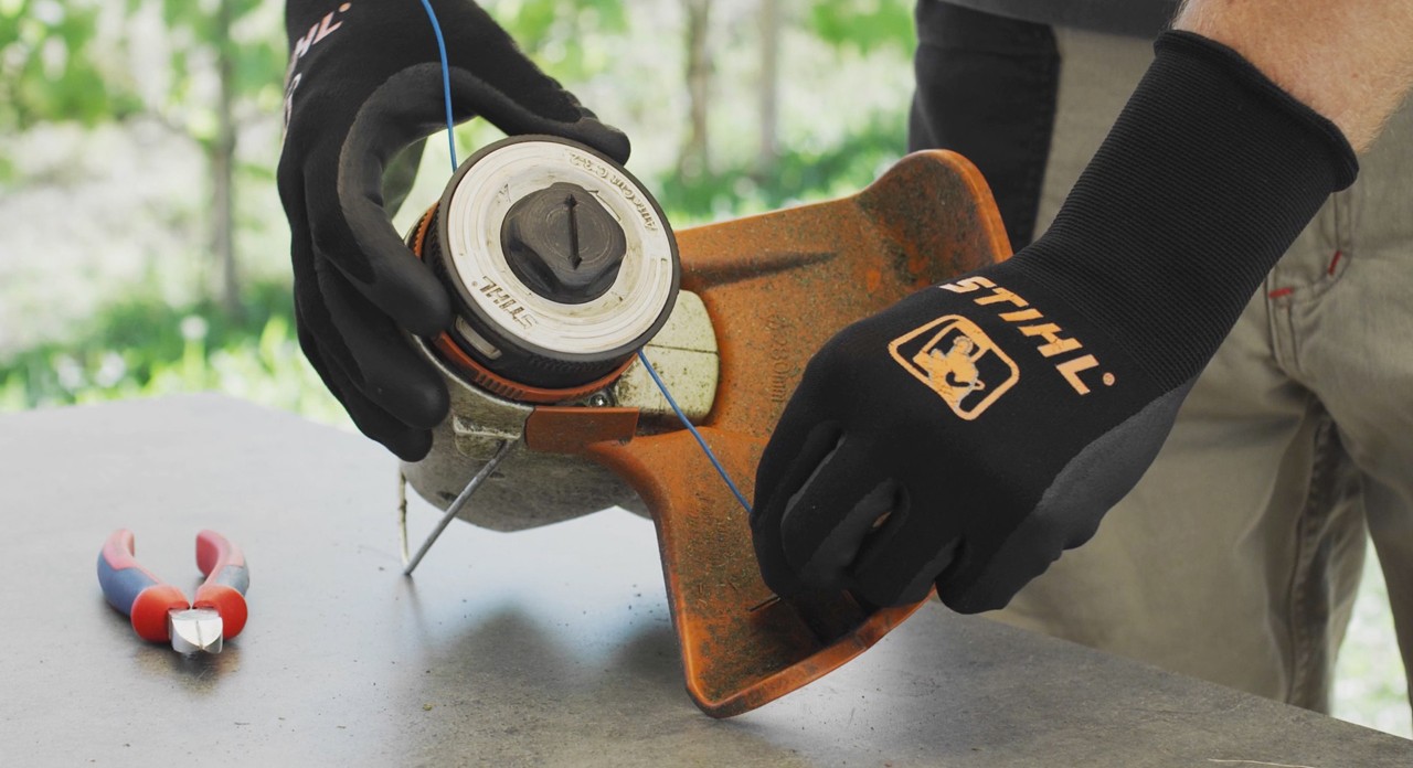 Osoba nawija żyłkę tnącą w akumulatorowej kosie mechanicznej STIHL FSA 57