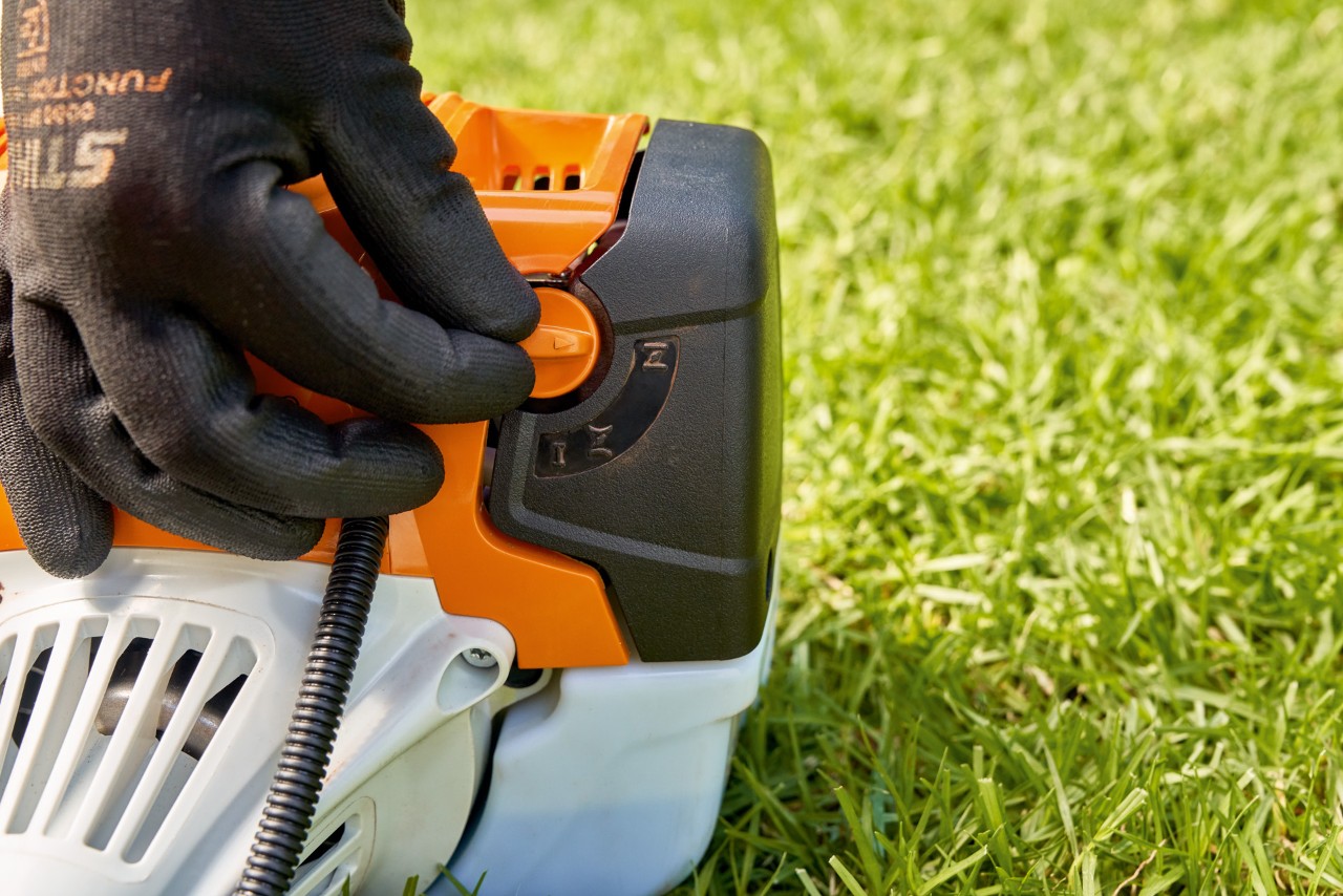Mężczyzna ustawia dźwignię pompy paliwa benzynowej kosy mechanicznej STIHL FS 91, aby ją uruchomić
