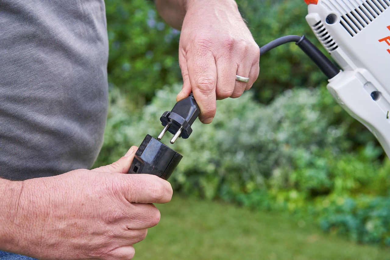 Mężczyzna w rękawicach ochronnych uruchamia dźwignię zmiany prędkości elektrycznej kosy mechanicznej STIHL FSE 60, aby ją uruchomić