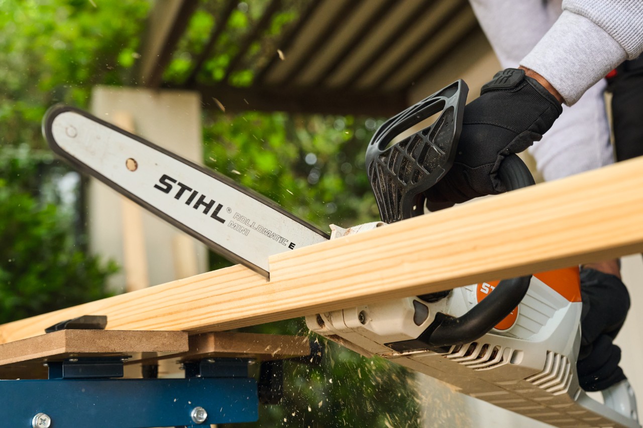 Mężczyzna piłuje poprzeczkę bramki piłkarskiej za pomocą STIHL MSA 70