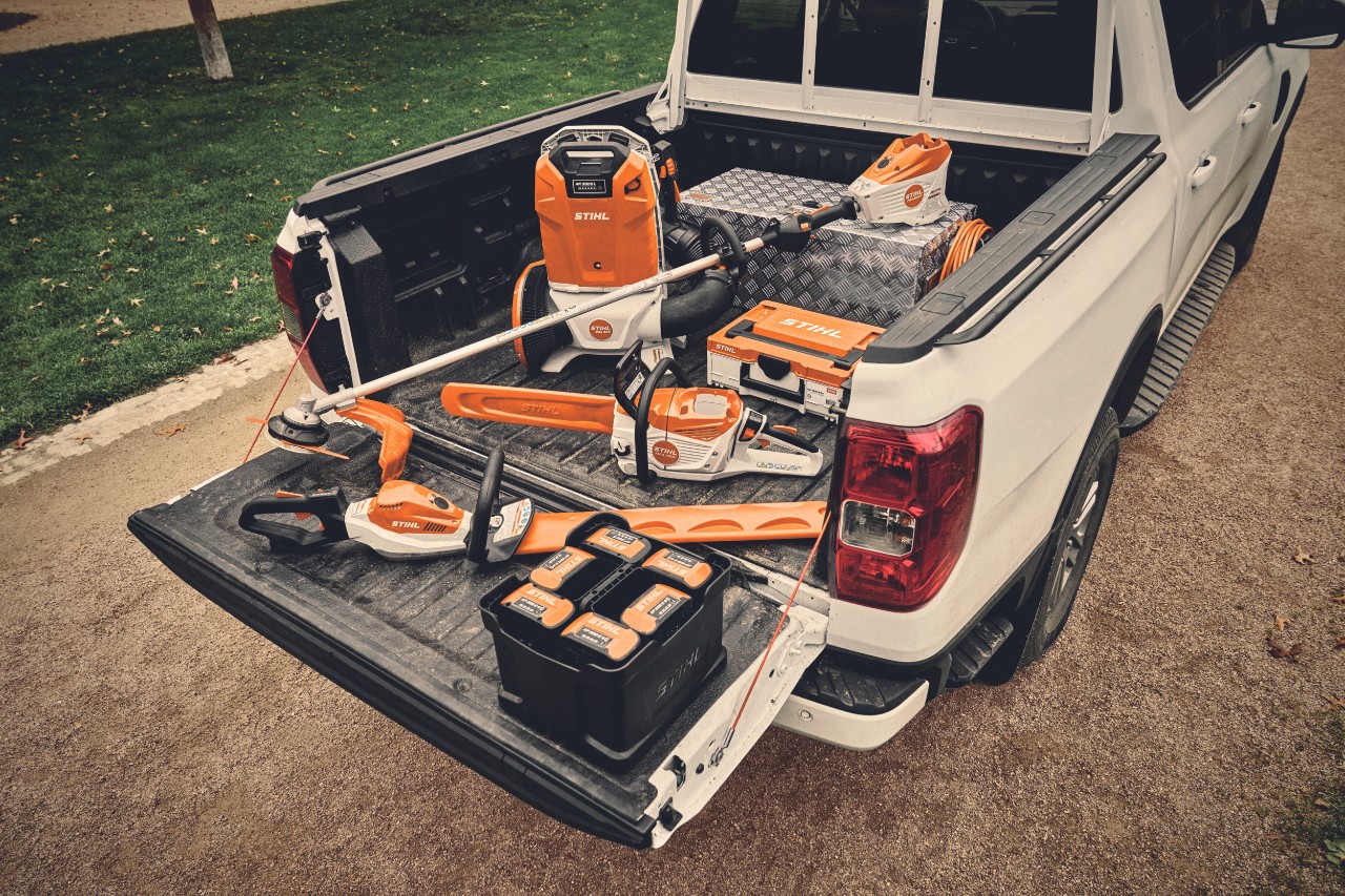 Różne narzędzia akumulatorowe z systemu STIHL AP i pasujące do nich akumulatory na powierzchni ładunkowej pojazdu