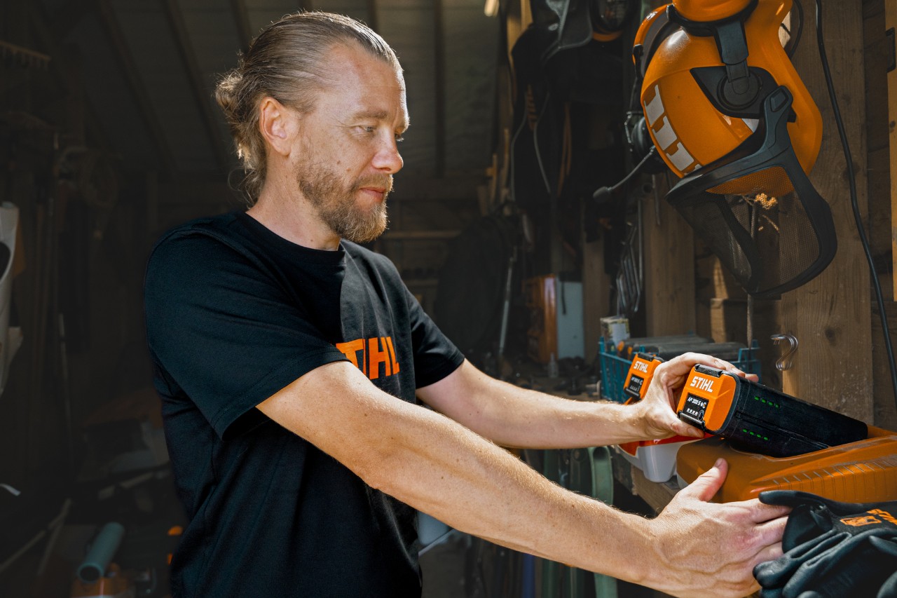 Andrew Wain wkłada akumulator do szybkoładowarki STIHL