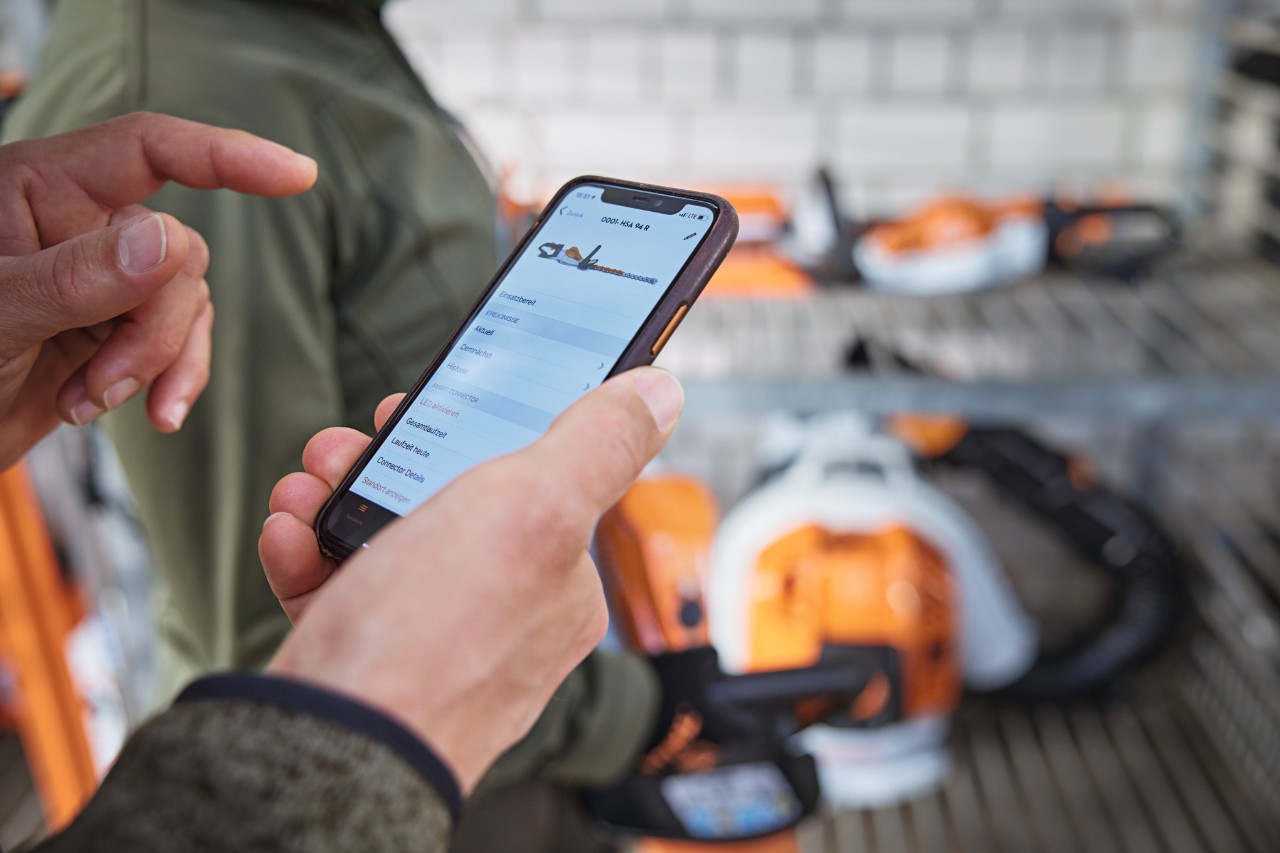 Osoba w magazynie sprawdza datę w aplikacji STIHL connected na smartfonie.