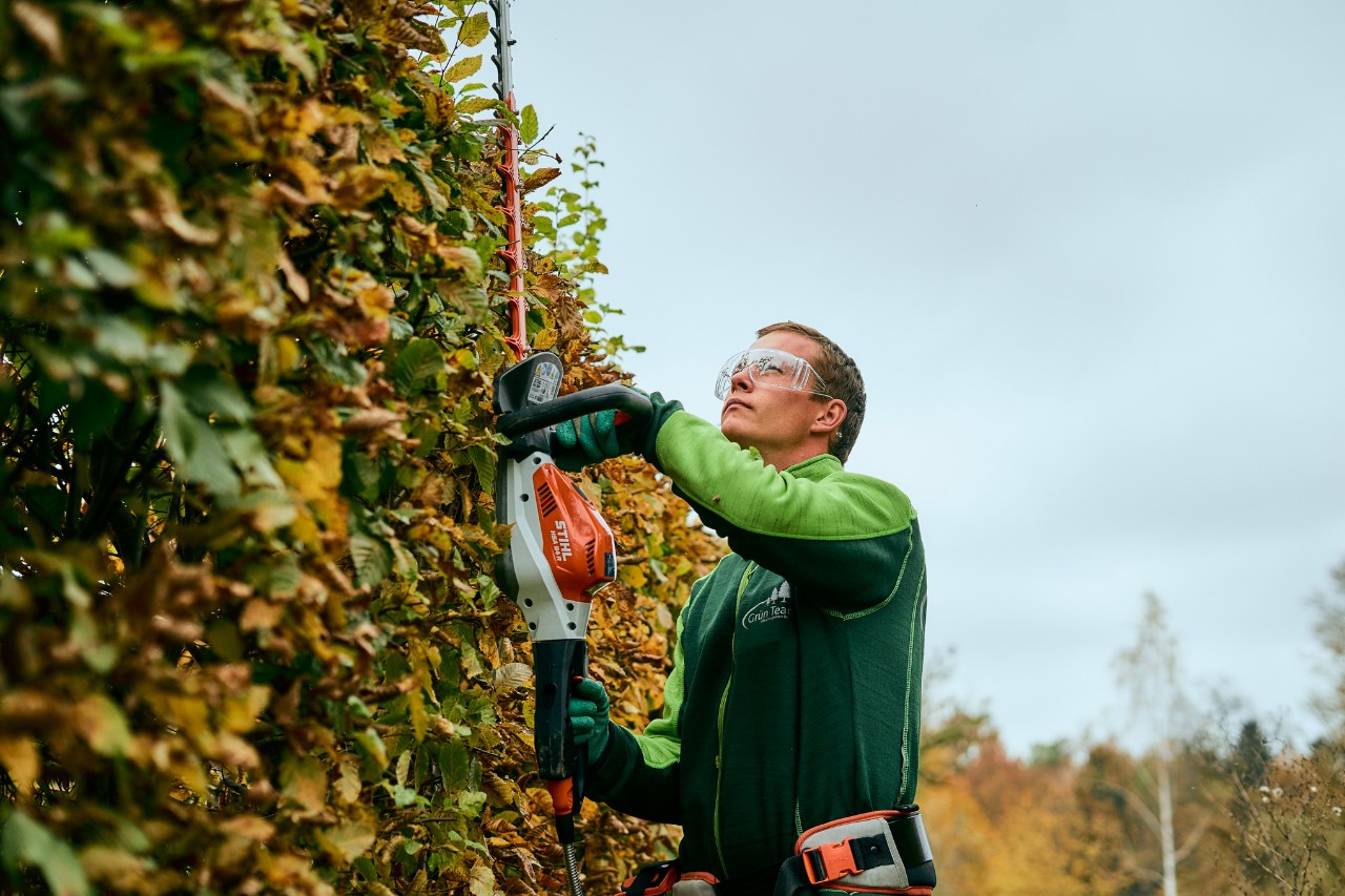 Mężczyzna przycinający żywopłot za pomocą nożyc do żywopłotu STIHL