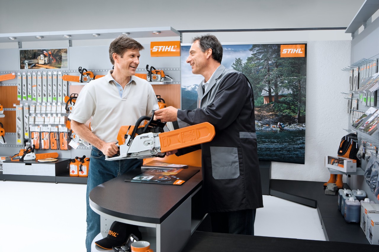 Dealer STIHL pokazuje klientowi pilarkę łańcuchową
