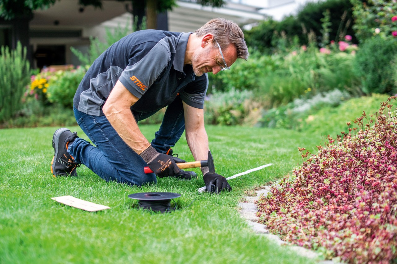 Sprzedawca STIHL układający przewód ograniczający