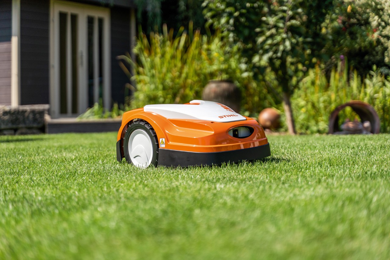 Robot koszący STIHL iMOW® RMI 422 na zielonej trawie przed domem 